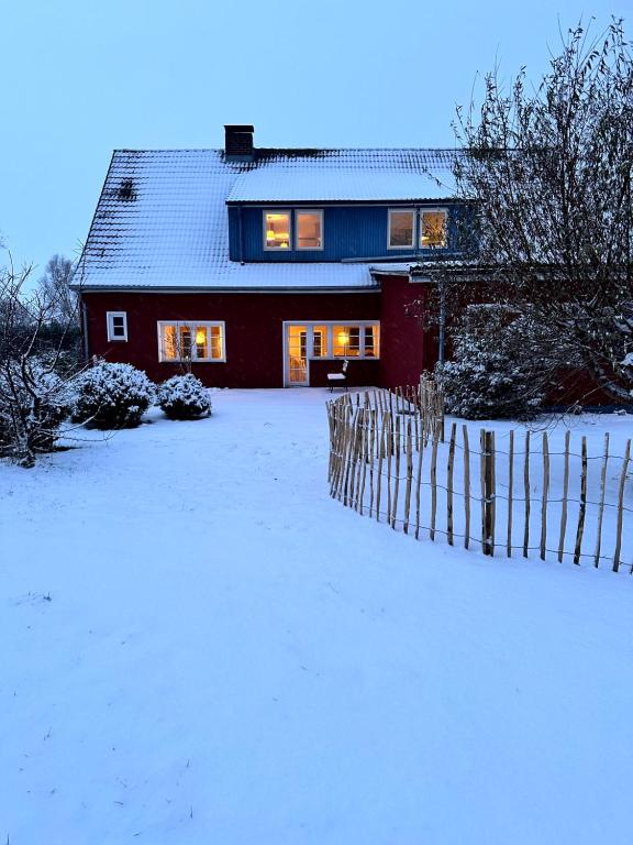 a red house with a fence in the snow at Ferienhaus am Saaler Bodden in Saal