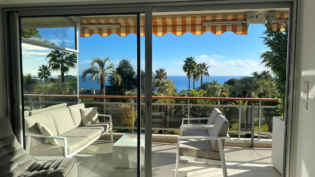 een woonkamer met glazen schuifdeuren en uitzicht op de oceaan bij APPARTEMENT 2 chambres vue mer panoramique, proche Croisette Cannes in Vallauris