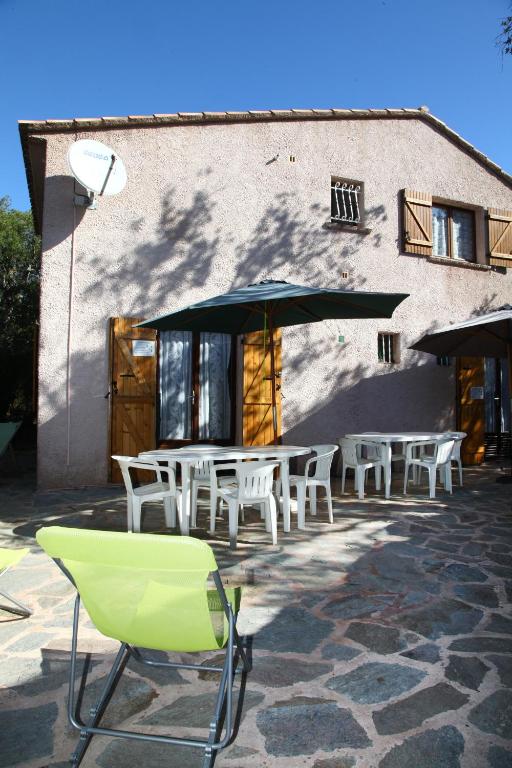 une table et des chaises avec un parasol en face d'un bâtiment dans l'établissement Mini villa Erbalunga, Santa Giulia, à Porto-Vecchio