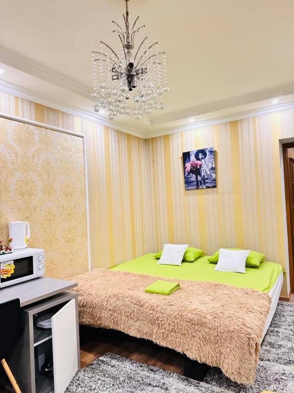een slaapkamer met een groen bed en een kroonluchter bij Apartments in City Center in Chişinău