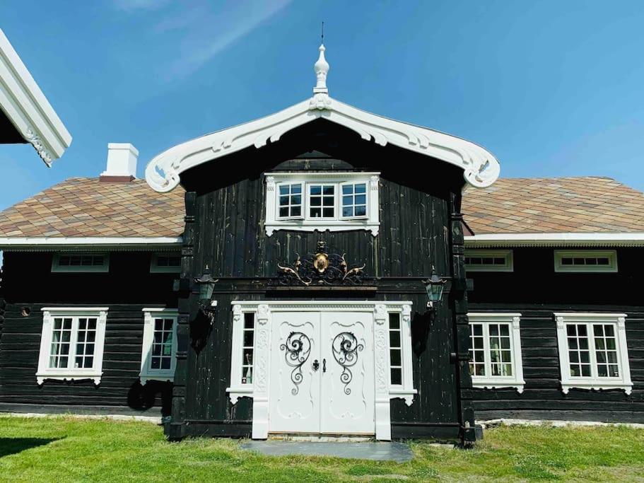 una casa en blanco y negro con una puerta blanca en Eventyrlig Tømmerhytte på Gårdstun, en Vinstra