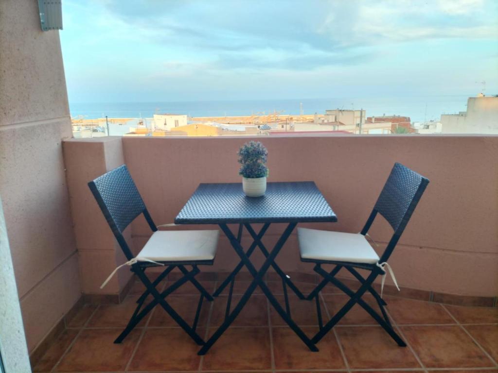 einen Tisch mit zwei Stühlen und eine Topfpflanze auf dem Balkon in der Unterkunft El Mirador de Garrucha in Garrucha