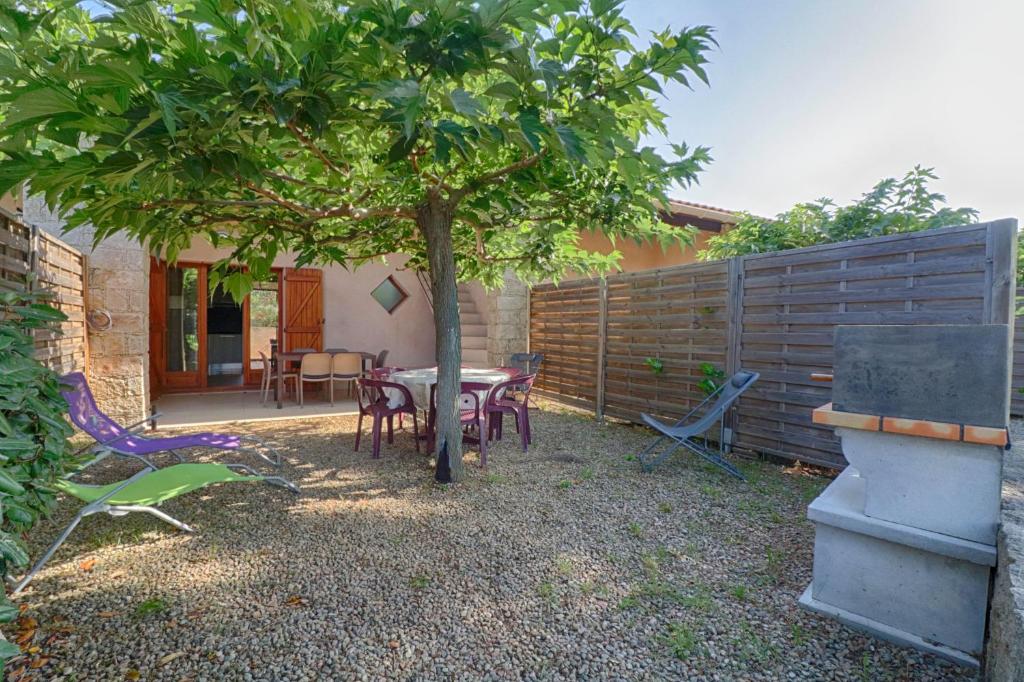 un patio avec une table et des chaises sous un arbre dans l'établissement Appartement n4 rez de jardin LA LISCIA, à Calcatoggio