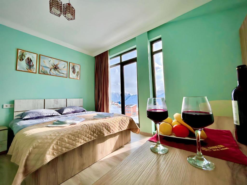 a bedroom with a bed and two glasses of wine at Dandelion Hotel Gudauri in Gudauri
