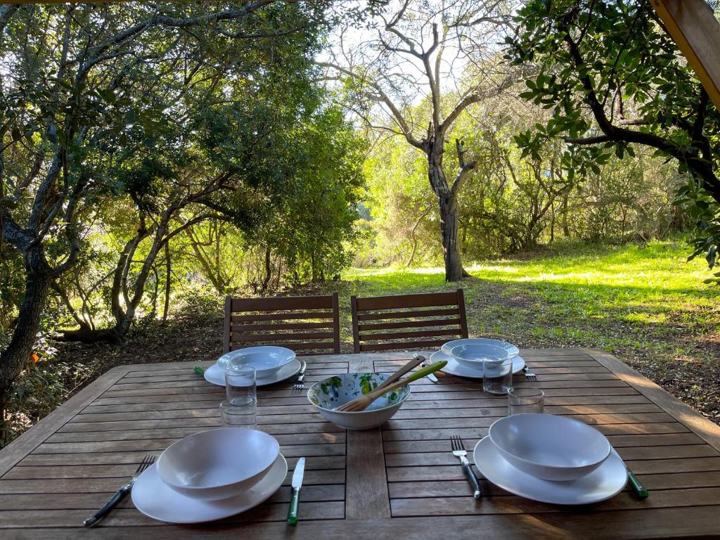 - une table en bois avec des assiettes et un bol de nourriture dans l'établissement Mini villa Centuri, Santa Giulia, à Porto-Vecchio