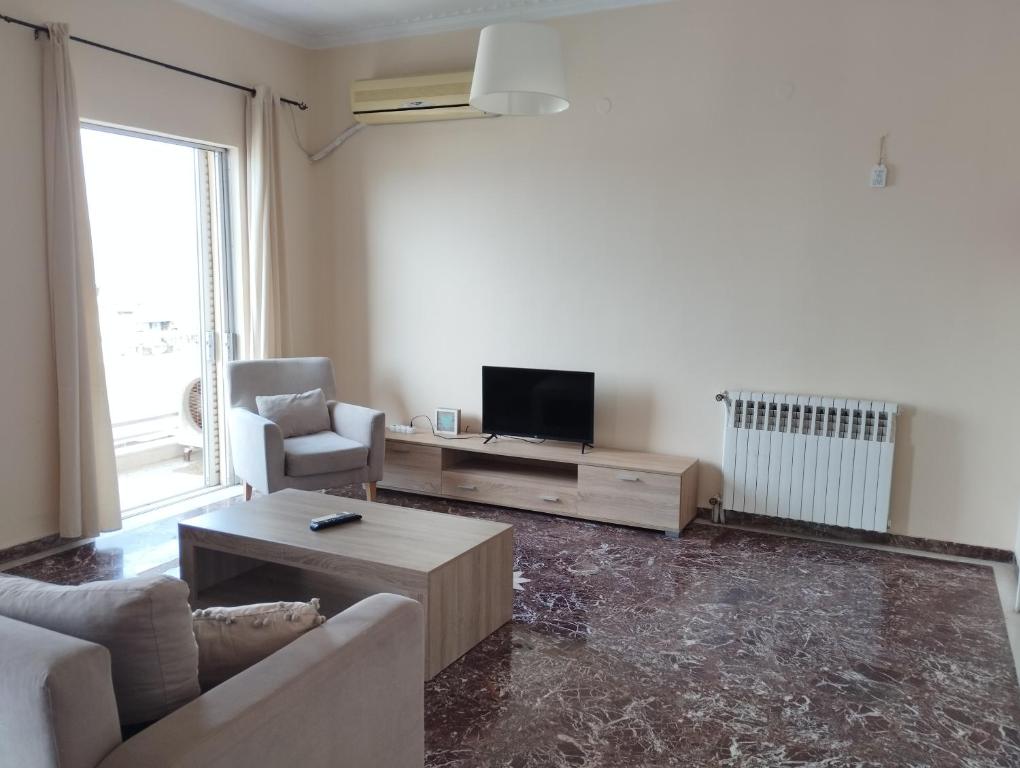 ein Wohnzimmer mit einem Sofa und einem TV in der Unterkunft Ionias Penthouse in Korinthos