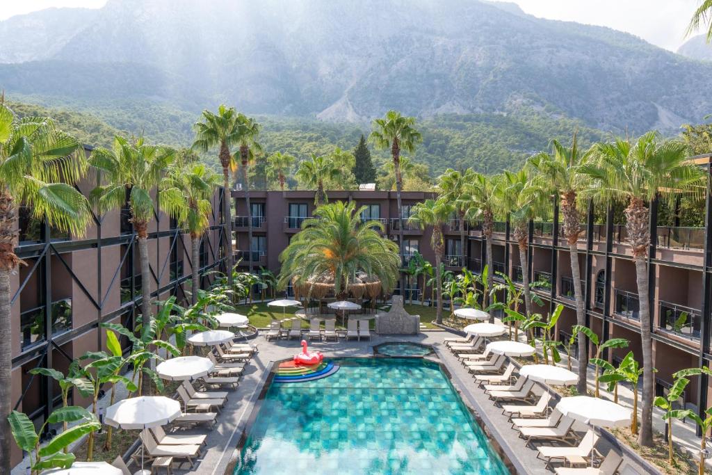 an outdoor pool with chaise lounge chairs and palm trees at Golden Sun Hotel Adult Only in Beldibi