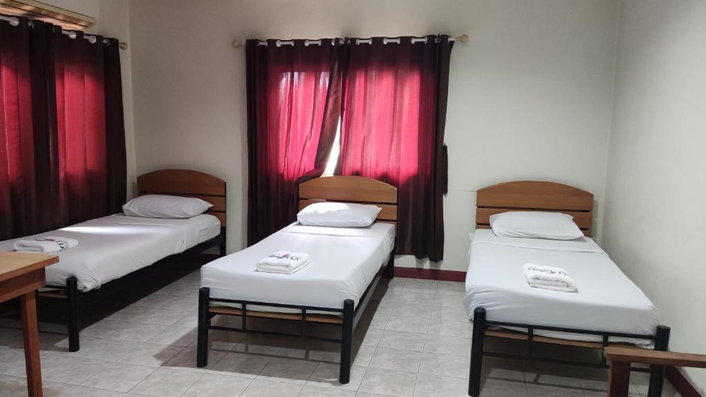 two beds in a room with red curtains at Toon guesthouse in Sukhothai