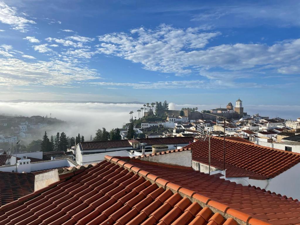 Blick auf die Dächer einer Stadt mit Wolken in der Unterkunft Mirador Templario in Jerez de los Caballeros