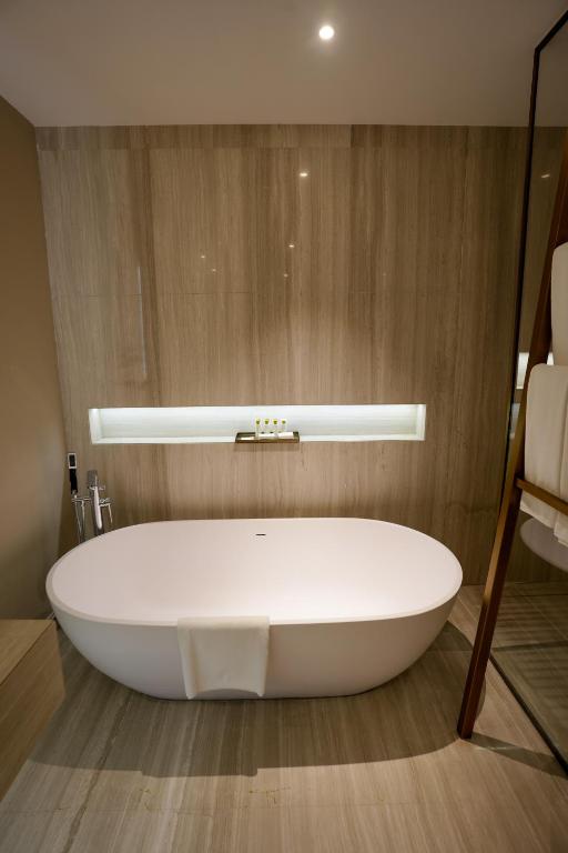 a white bath tub in a room with a wooden wall at Mirfa Hotel in Al Mirfa