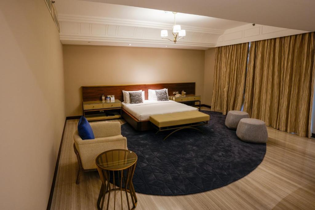 a hotel room with a bed and a couch and chairs at Mirfa Hotel in Al Mirfa