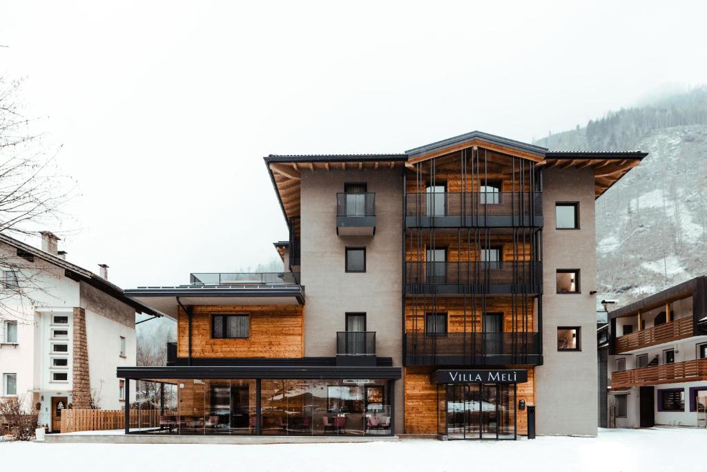 un edificio en las montañas con nieve en el suelo en Hotel Villa Melì en Predazzo