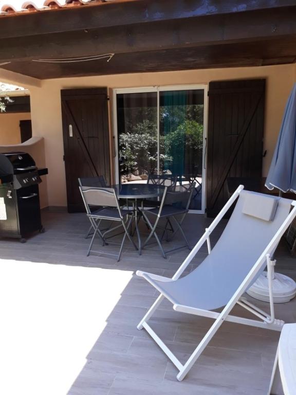 - un hamac sur une terrasse avec une table et des chaises dans l'établissement Villa Occhiatana, Santa Giulia, à Porto-Vecchio