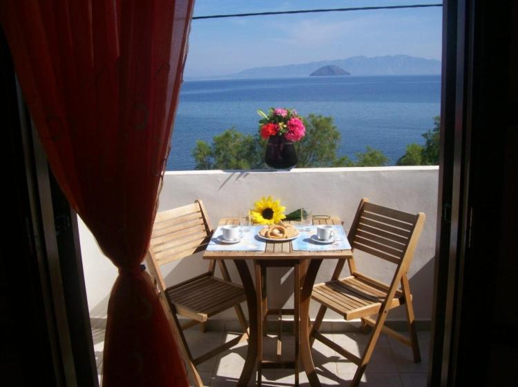 einen Tisch und Stühle auf einem Balkon mit Meerblick in der Unterkunft Pali Nisyros Hotel in Páloi