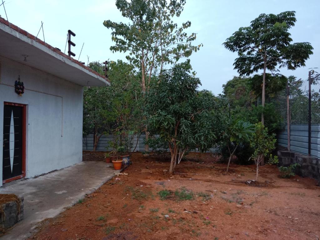 einen Hof mit Bäumen neben einem weißen Gebäude in der Unterkunft Goud's Home stay in New Hampi
