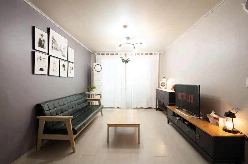 sala de estar con sofá verde y TV en Ria House en Goyang