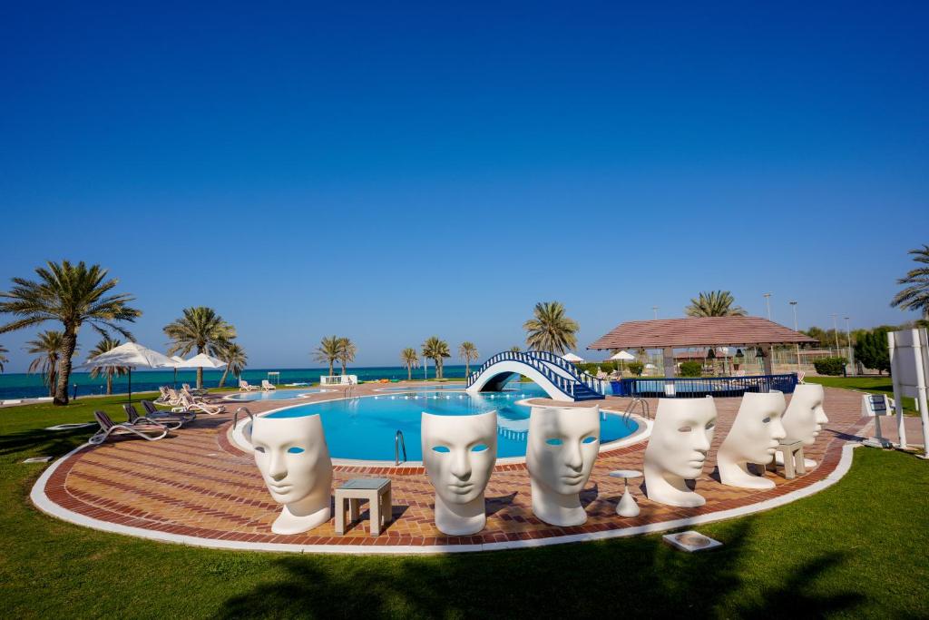 a pool at a resort with white statues around it at Mirfa Hotel in Al Mirfa