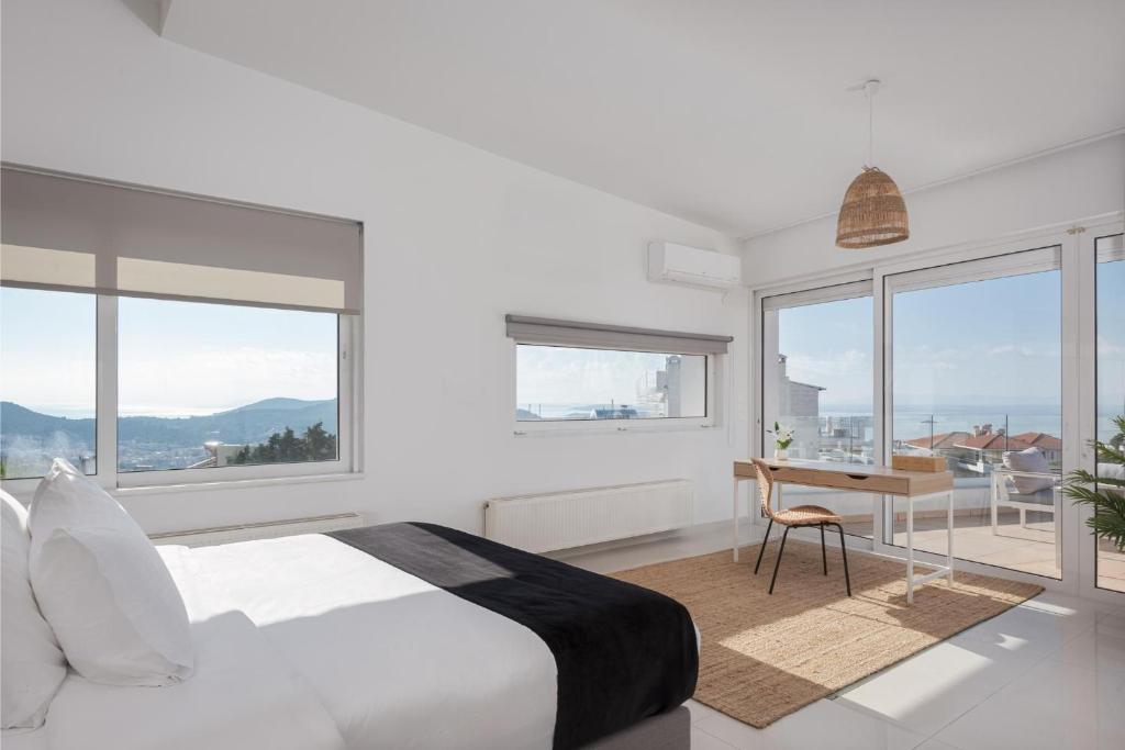 a white bedroom with a bed and a desk and windows at Athenian Riviera Panorama Villa in Athens