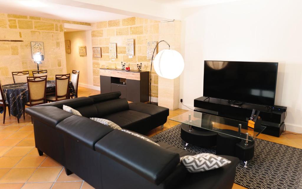 a living room with a black leather couch and a flat screen tv at Pomerol au Cœur in Pomerol