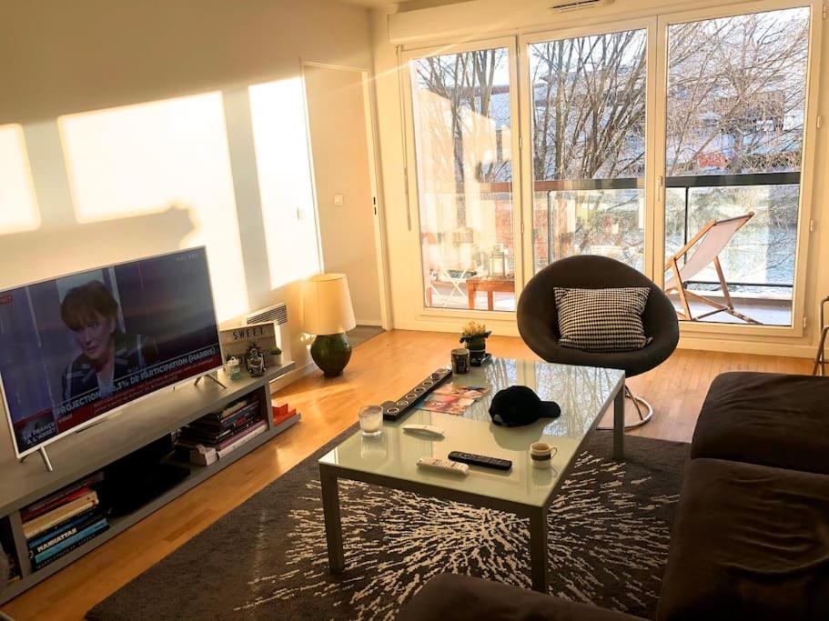 - un salon avec une télévision, une chaise et une table dans l'établissement 4 pièces au Stade de France 80 m2, à Saint-Denis