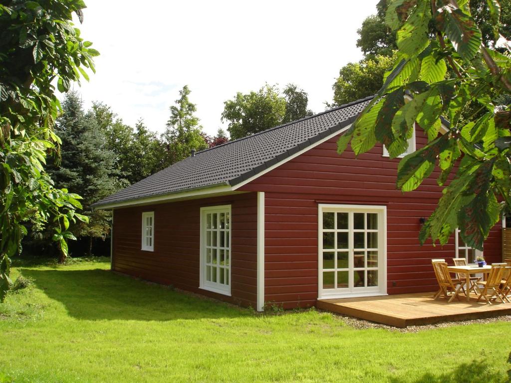 a red cabin with a deck and a table at Ferienhof Kolauerhof - Bauernhofurlaub in Grömitz in Grömitz