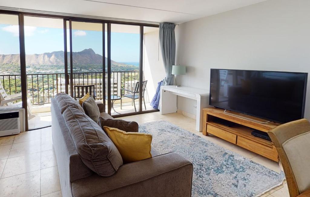 a living room with a flat screen tv and a couch at Sleek & Modern 32nd Floor Condo at the Waikiki Banyan - Free parking! condo in Honolulu
