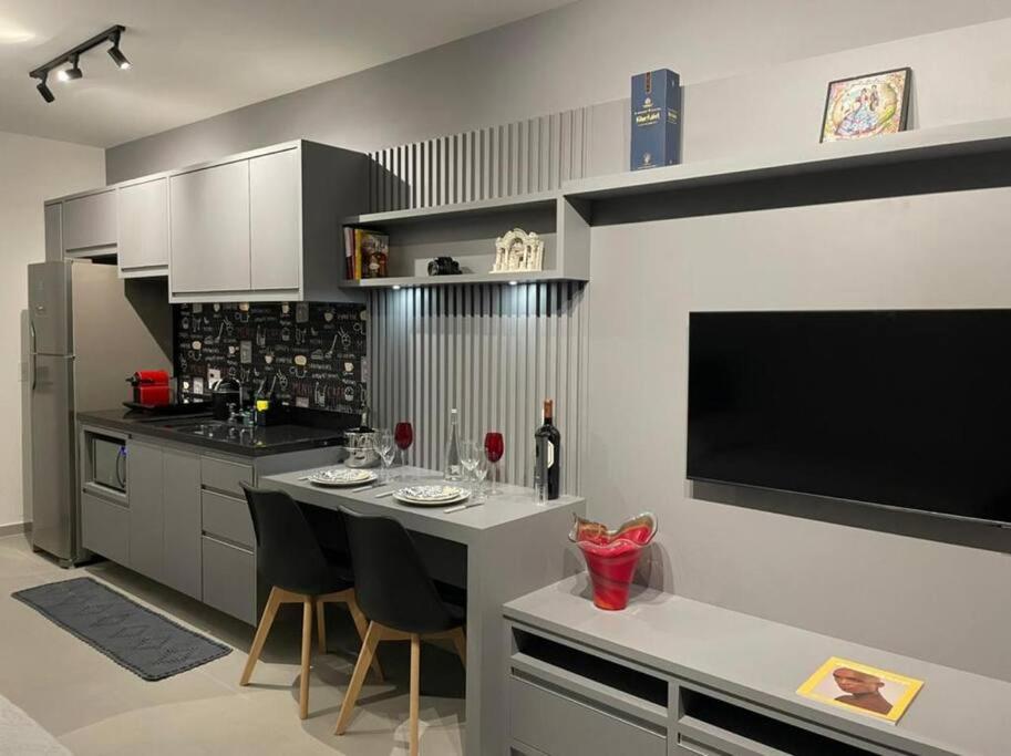 a kitchen with a bar with chairs and a flat screen tv at Studio Metrô Brooklin in Sao Paulo