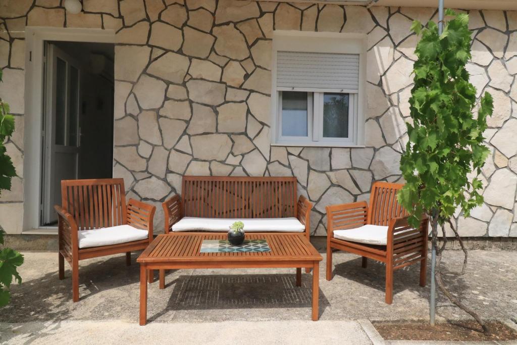 three wooden chairs and a table in front of a building at Apartments Vjera Rukavac in Rukavac