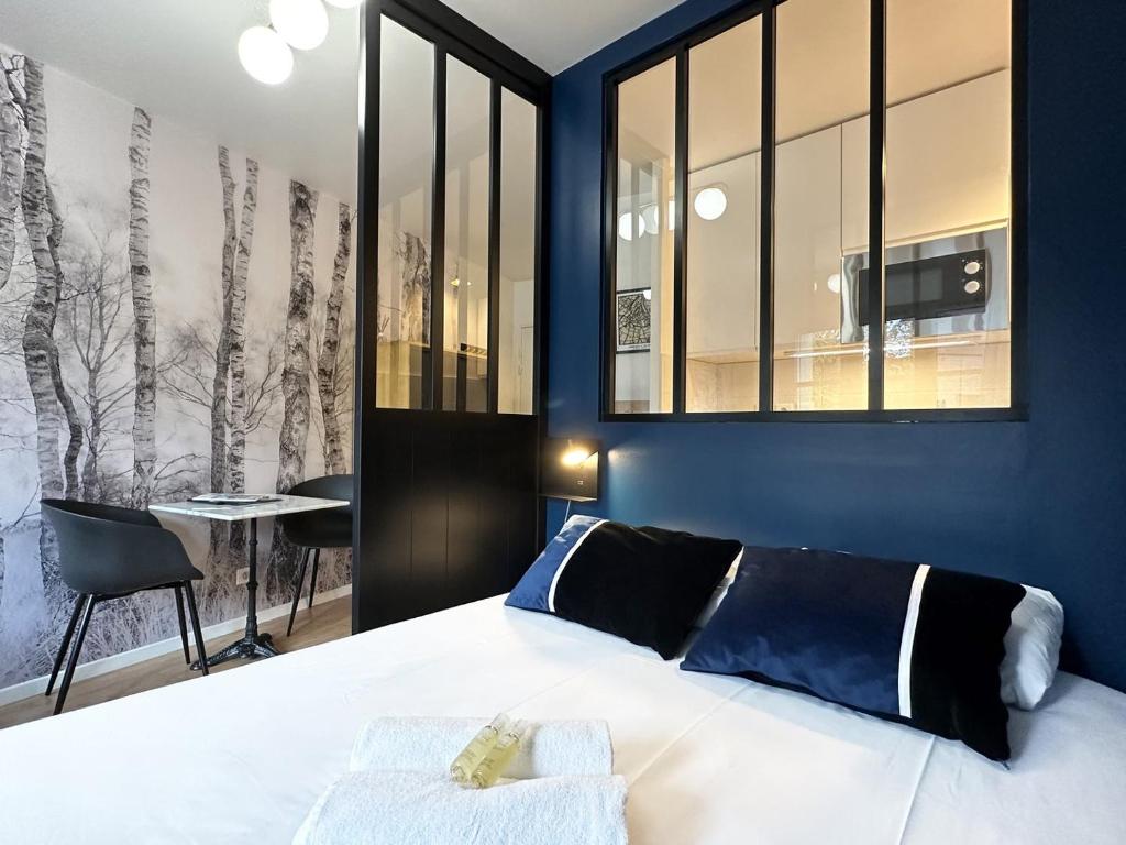 Schlafzimmer mit einem Bett mit blauen Wänden und Fenstern in der Unterkunft C le 15 - Studio Cosy avec Parking in Chartres