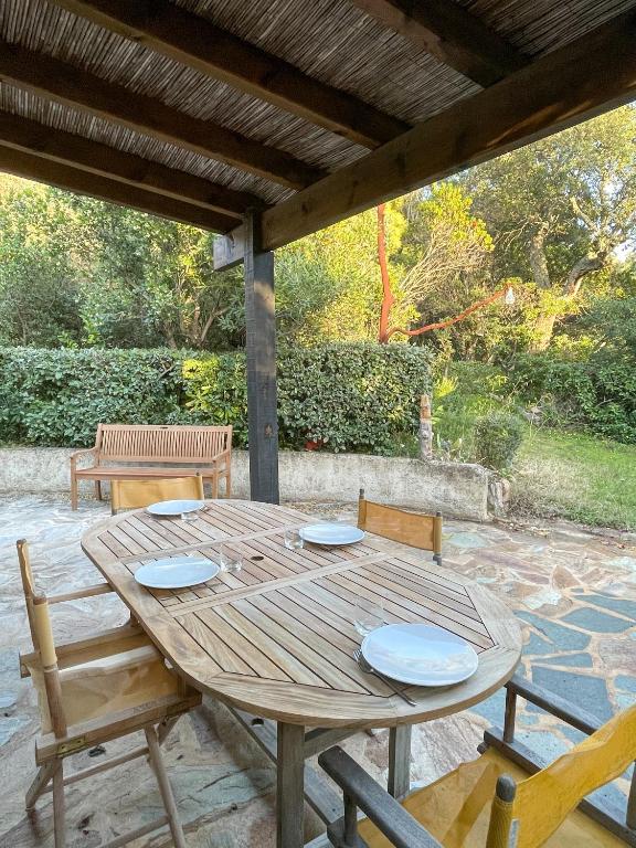 une table et des chaises en bois sous un toit en bois dans l'établissement Maison Asco à Santa Giulia, à Porto-Vecchio