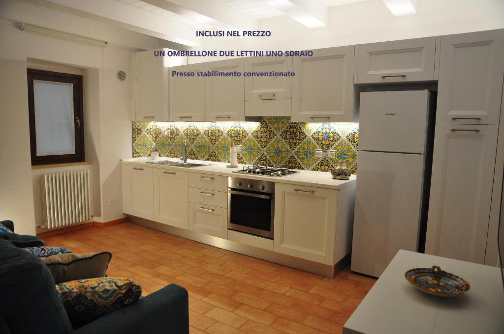 eine Küche mit weißen Schränken, einem Herd und einem Kühlschrank in der Unterkunft Casa Vacanze Torre dei Gualtieri in San Benedetto del Tronto
