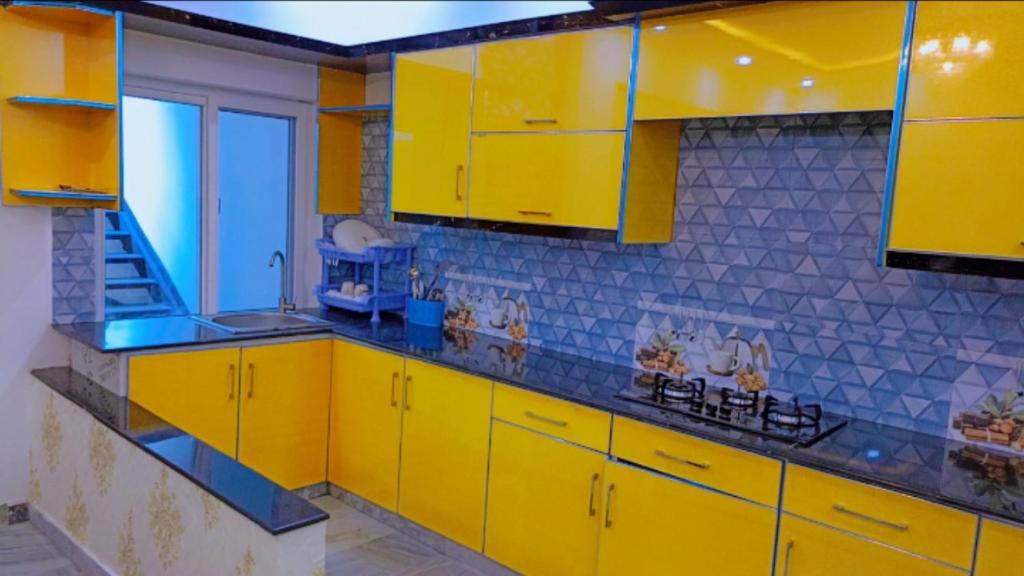 a yellow kitchen with yellow cabinets and blue tiles at BED AND BREAKFAST ISLAMABAD - cottages in Islamabad