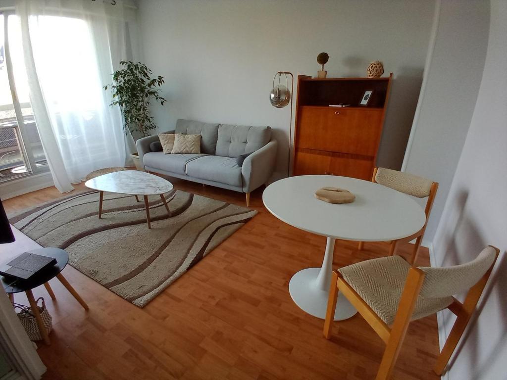 a living room with a table and a couch at Appartement avec parking et balcon vue Cathédrale in Chartres