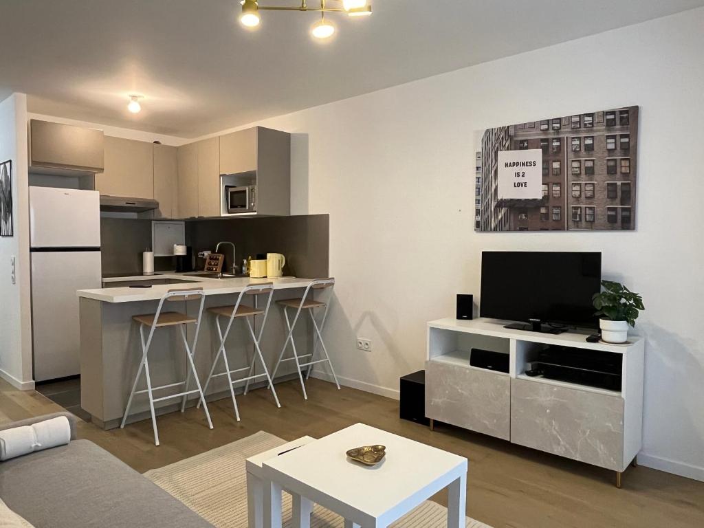 a living room with a kitchen with a counter and a tv at GoodGuest-Cosy Apartment New Bulding Clichy-4 PAX in Clichy