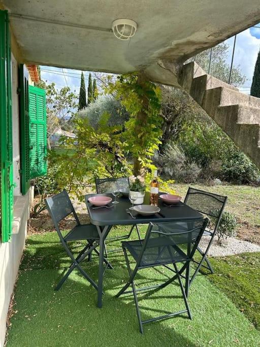 une table et des chaises noires assises sur l'herbe dans l'établissement Typique cabanon provençal rénové Attention escalier extérieur pour accéder au 1er étage, à Gonfaron