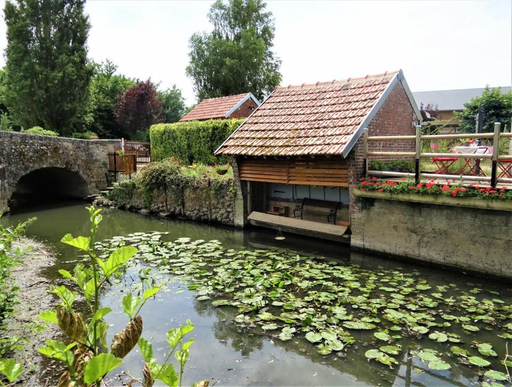 una casa con un puente y un estanque con lirios en Le Lavoir Secret - hébergement atypique dans un joli cadre bucolique, en Dangeau