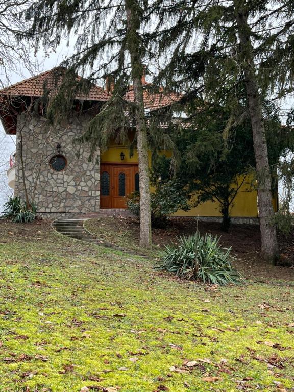 une maison en pierre avec un arbre en face de celle-ci dans l'établissement Klára Villa, à Balatonboglár
