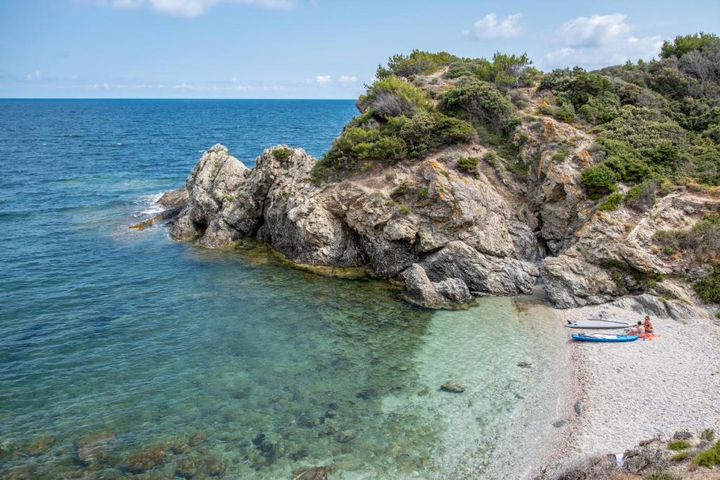 a beach with a boat in the water at Hôtel Helios &amp; SPA - Ile des Embiez in Six-Fours-les-Plages