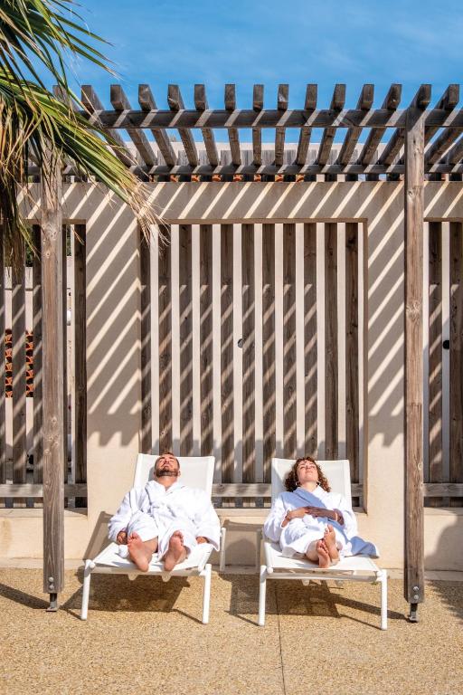 two people are laying in chairs on the beach at Hôtel Helios &amp; SPA - Ile des Embiez in Six-Fours-les-Plages