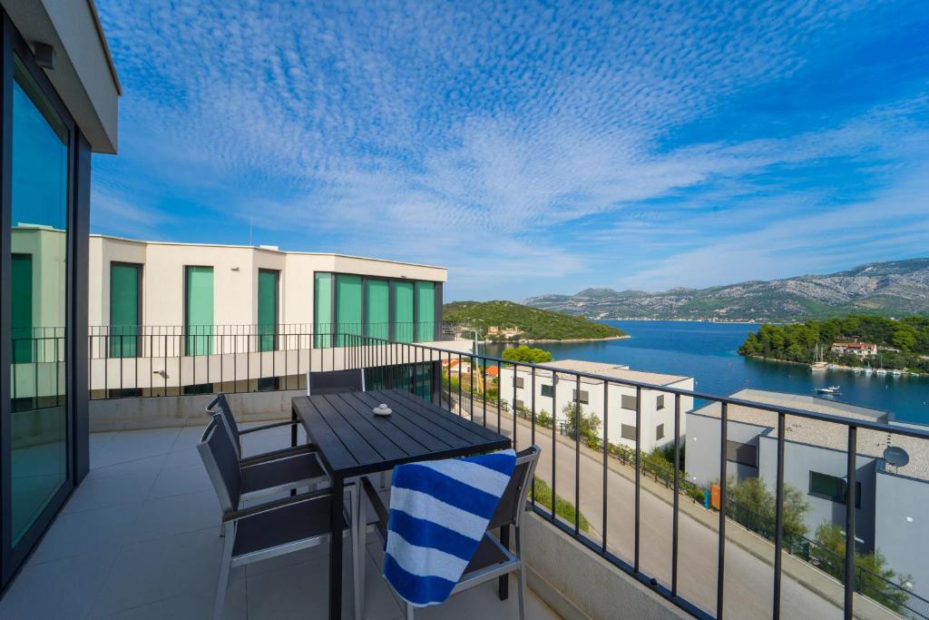 a balcony with a table and chairs and a view of the water at White Cloud Apartments in Korčula