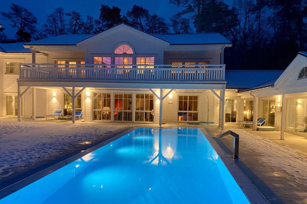 a house with a swimming pool at night at Panorama Hotel am Oberuckersee in Warnitz