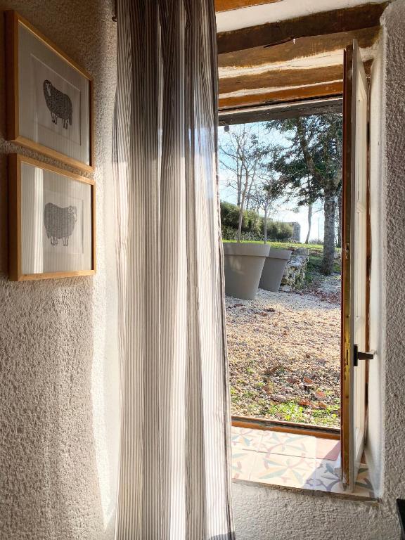 an open door to a yard with a window at Gîte de charme avec grand jardin &amp; piscine in Touffailles