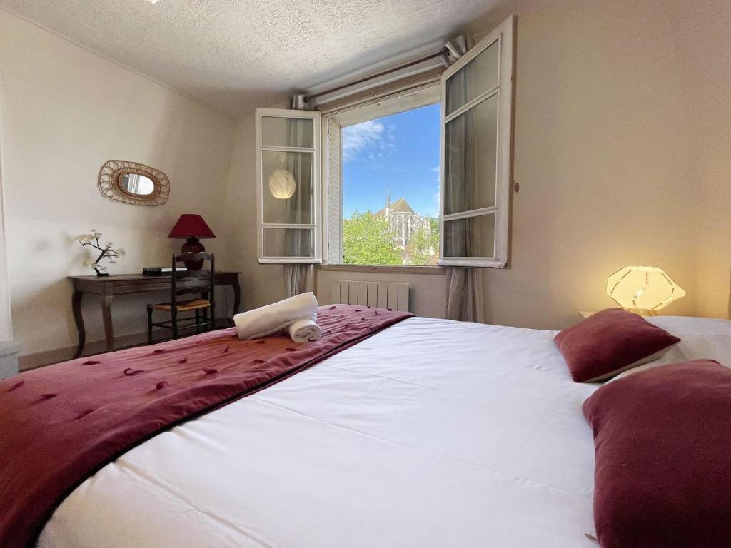 une chambre avec un grand lit blanc avec une fenêtre dans l'établissement Au fil de l’Eure, quartier authentique et plein de charme, à Chartres
