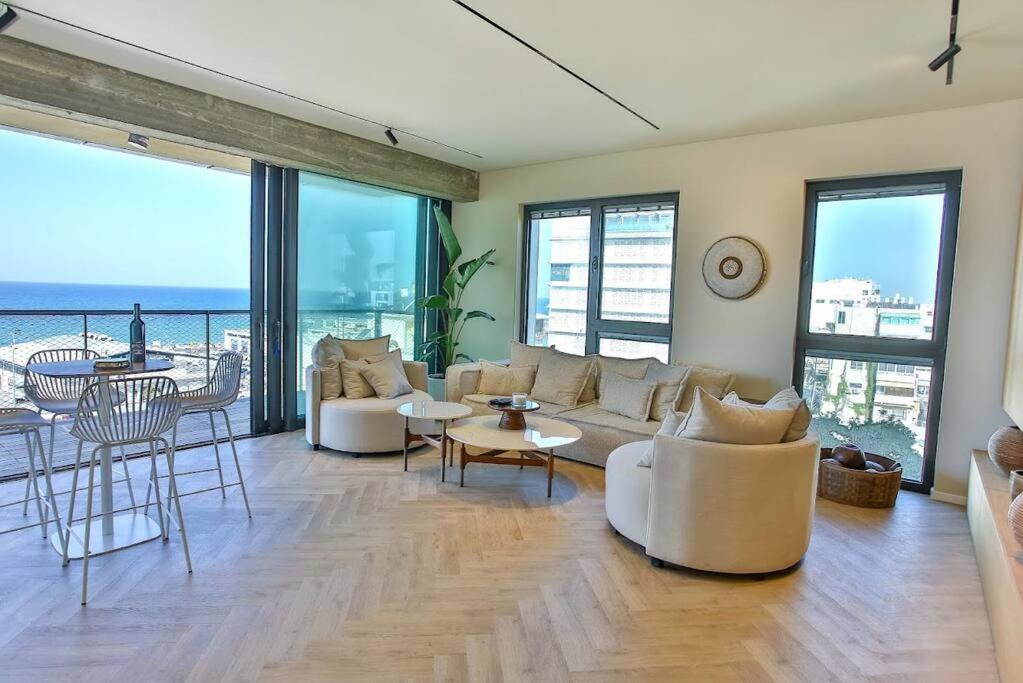 una sala de estar con muebles blancos y vistas al océano. en High End 1BD Beach Apartment, en Tel Aviv