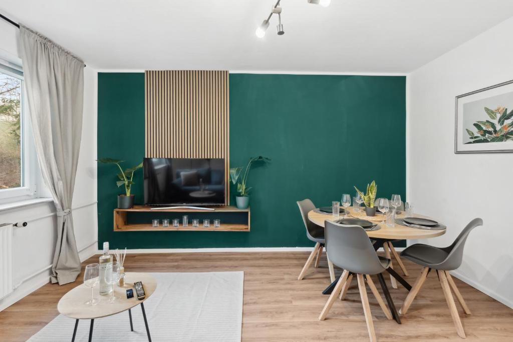 a dining room with green walls and tables and a tv at Stadt-Apartment 3 Zimmer mit Terasse in Hannover