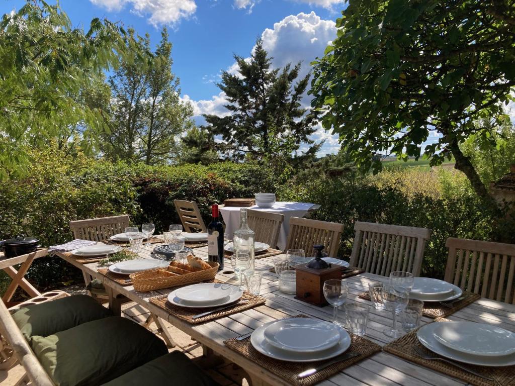 a wooden table with plates and glasses on it at Gîte de charme avec grand jardin &amp; piscine in Touffailles