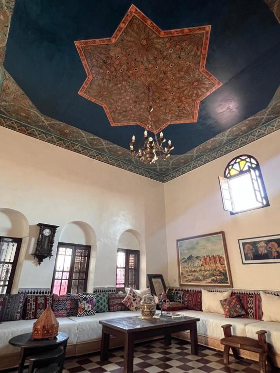 een woonkamer met een plafond met een kroonluchter bij dar said in Rabat