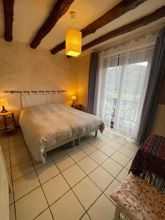 a bedroom with a bed and a large window at chambres d'hôtes las Vignes in Beaucens
