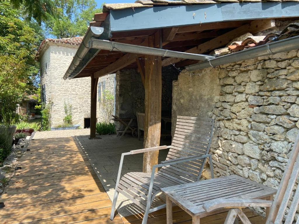 a wooden bench sitting under an awning on a patio at Gîte de charme avec grand jardin &amp; piscine in Touffailles