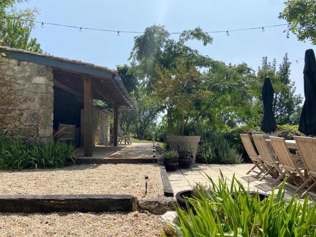 a patio with chairs and umbrellas in a garden at Gîte de charme avec grand jardin &amp; piscine in Touffailles